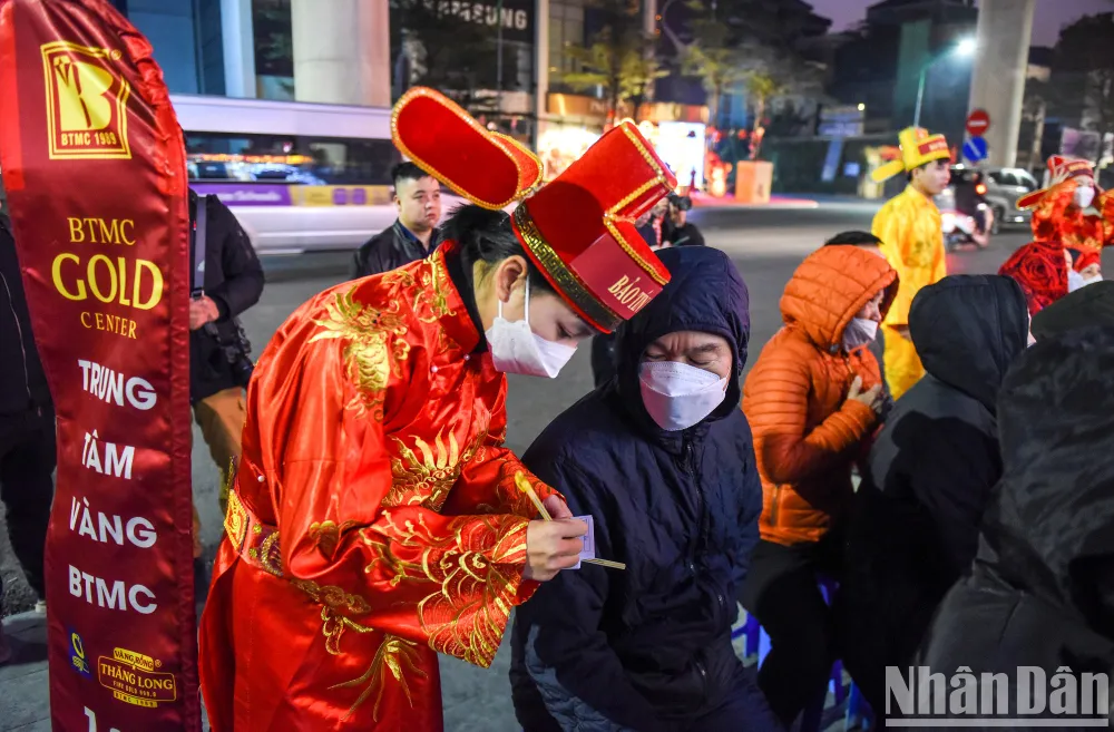 Càng tới gần thời điểm 6 giờ 30 phút, lượng khách tới càng đông. Các nhân viên trong trang phục Thần Tài hướng dẫn khách hàng đăng ký số để chuẩn bị mua vàng cầu may dịp đầu năm.