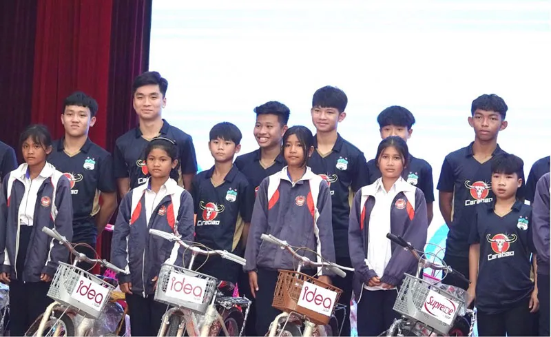Cầu thủ Học viện HAGL cùng các em học sinh nhận xe đạp.