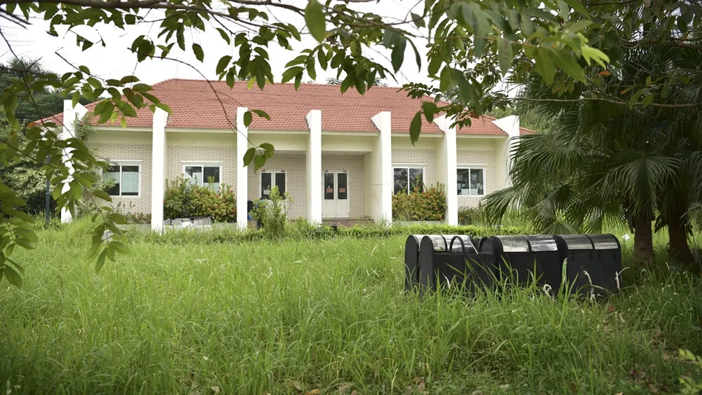 Khu nhà điều hành trong công viên bị bao quanh bởi cỏ dại, che mất lối đi.
