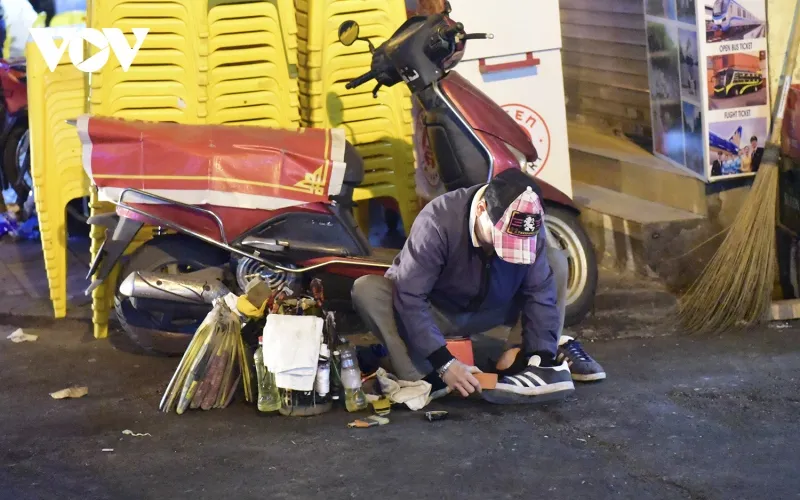 Dù đã 12h đêm, một người đàn ông vẫn cố nán lại để đánh dày cho khách ở phố Cổ Hà Nội.