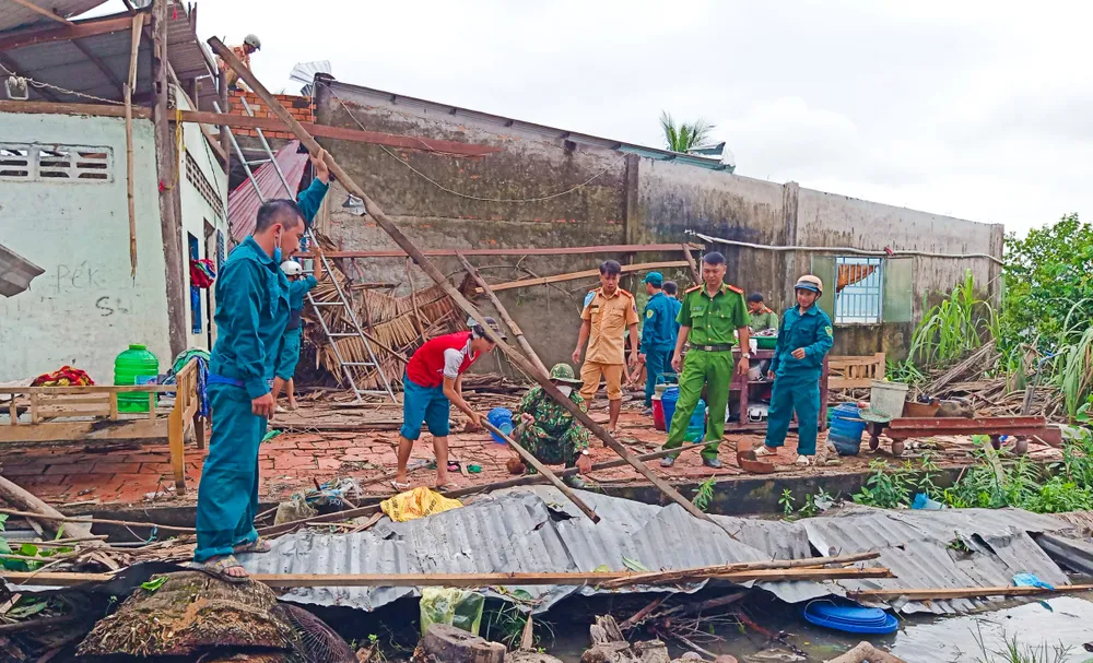 Lực lượng chức năng địa phương giúp dân dọn dẹp nhà cửa do lốc xoáy gây ra - Ảnh: LÊ VŨ