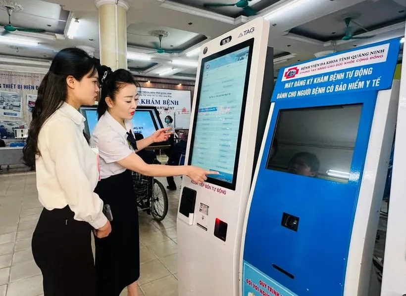 Nhân viên y tế hướng dẫn người dân tại máy đăng ký khám bệnh tự động ở Bệnh viện Đa khoa tỉnh Quảng Ninh. (Ảnh: T.G/Vietnam+) 
