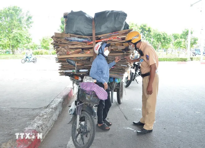 Trường hợp xe máy gắn xe lôi tự chế chở hàng quá kích cỡ quy định. (Ảnh: Linh Sơn/TTXVN)