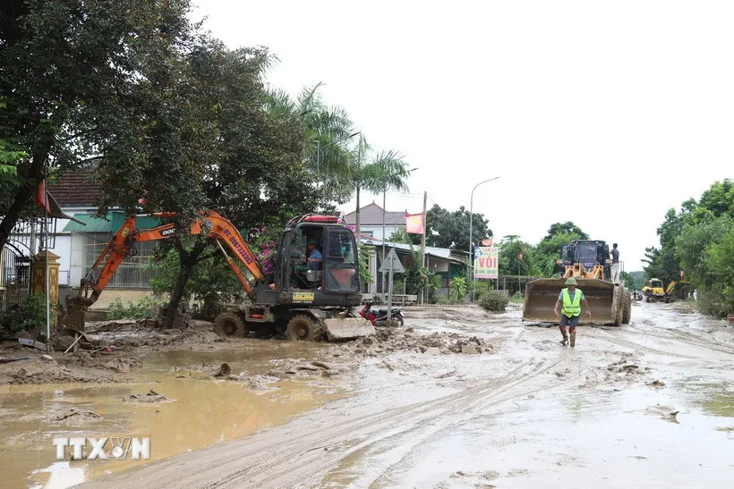 Máy cẩu, máy xúc được huy động tham gia vào việc san ủi bùn đất, sinh lầy tại một điểm ngập trên tuyến quốc lộ 7 qua địa bàn xã Con Cuông, tỉnh Nghệ An. (Ảnh: Xuân Tiến/TTXVN)
