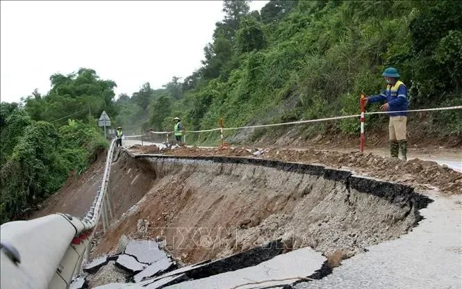 Lực lượng chức năng tỉnh Nghệ An đã bố trí người cắm thiết bị cảnh bảo ở các điểm sạt lở cho các phương tiện giao thông đi qua. Ảnh: TTXVN 