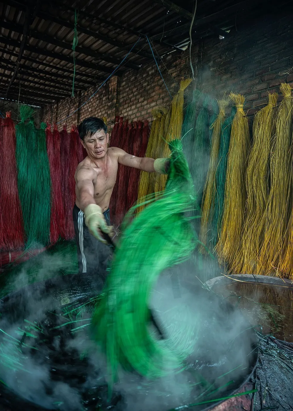 Sợi cói phải được nhúng đều vào nước nhuộm đang đun sôi để giữ được màu tươi lâu hơn. Ảnh: Khánh Hoà – TTXVN