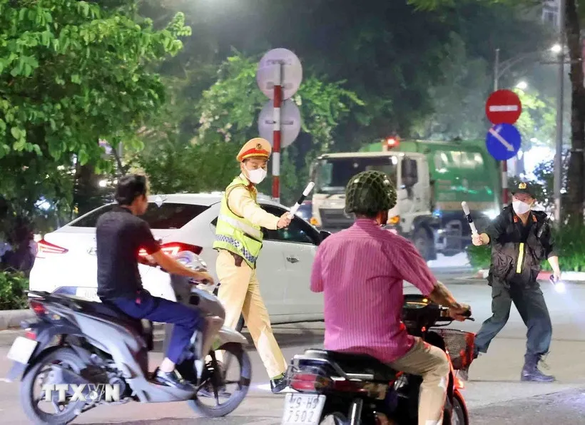 Cán bộ, chiến sỹ thuộc tổ công tác liên ngành Y6/141 dừng xe kiểm tra và xử lý 1 trường hợp vi phạm giao thông. (Ảnh: Phạm Kiên/TTXVN) 