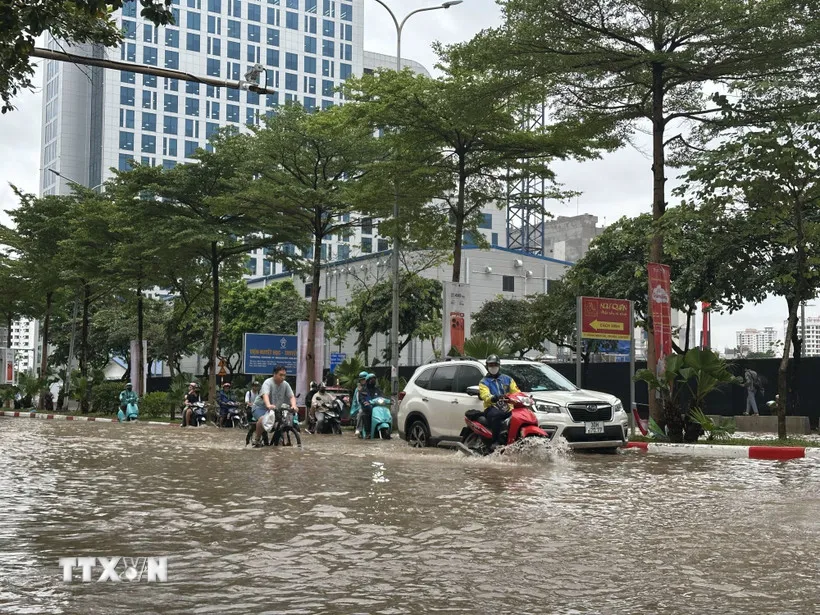 Người dân di chuyển qua tuyến phố Trung Kính bị ngập lụt sau mưa lớn. (Ảnh: Huy Hùng/TTXVN)