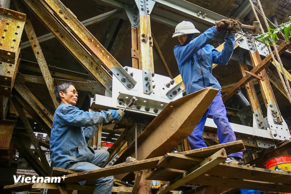 Công nhân đang tiến hành gia cố lan can và dầm cầu, tập trung xử lý các vị trí hư hỏng, xuống cấp sau thời gian dài sử dụng. (Ảnh: Hoài Nam/Vietnam+)