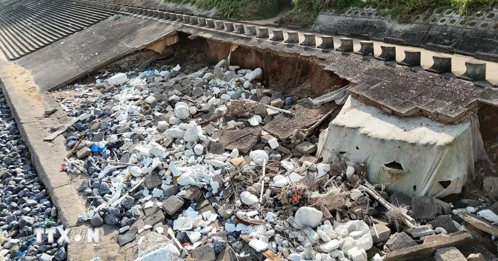 Đoạn kè ven biển dài khoảng 60m bị sóng biển khoét sâu vào trong, lộ ra xi măng, cốt thép, đất... (Ảnh: Thanh Thủy/TTXVN) 