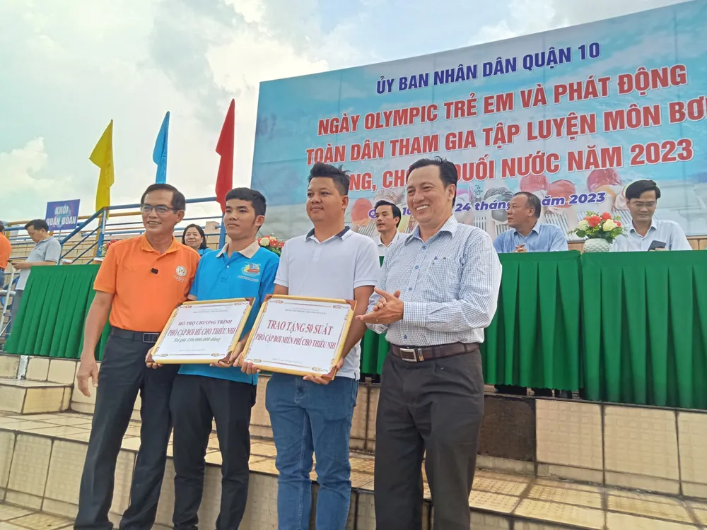 Ông Phạm Hữu Tâm ,Tổng Thư ký Liên đoàn Thể thao dưới nước TPHCM (bìa phải) và ông Nguyễn Anh Tuấn, Giám đốc Trung tâm TDTT quận 10, trao tặng các suất học bơi miễn phí và phổ cập bơi hè cho thiếu nhi trên địa bàn quận