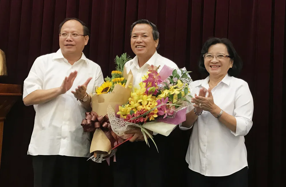 Đồng chí Tất Thành Cang và đồng chí Thân Thị Thư, Ủy viên Ban Thường vụ Thành ủy TPHCM, trao quyết nghỉ hưu và tặng hoa cho đồng chí Huỳnh Văn Chúm (giữa). Ảnh: KIỀU PHONG