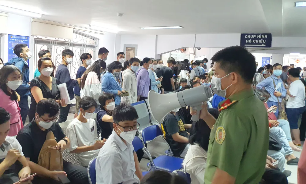 Cán bộ Phòng PA08 thông báo về việc tạm ngưng cấp số thứ tự và hướng dẫn người dân đăng ký cấp hộ chiếu online. Ảnh: NGÔ BÌNH