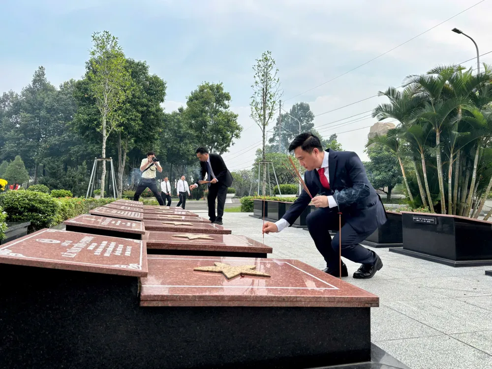 Phó Bí thư Thành ủy TPHCM Đặng Minh Thông và Phó Chủ tịch UBND TPHCM Nguyễn Lộc Hà thắp hương từng phần mộ liệt sĩ. Ảnh: VĂN CHÂU