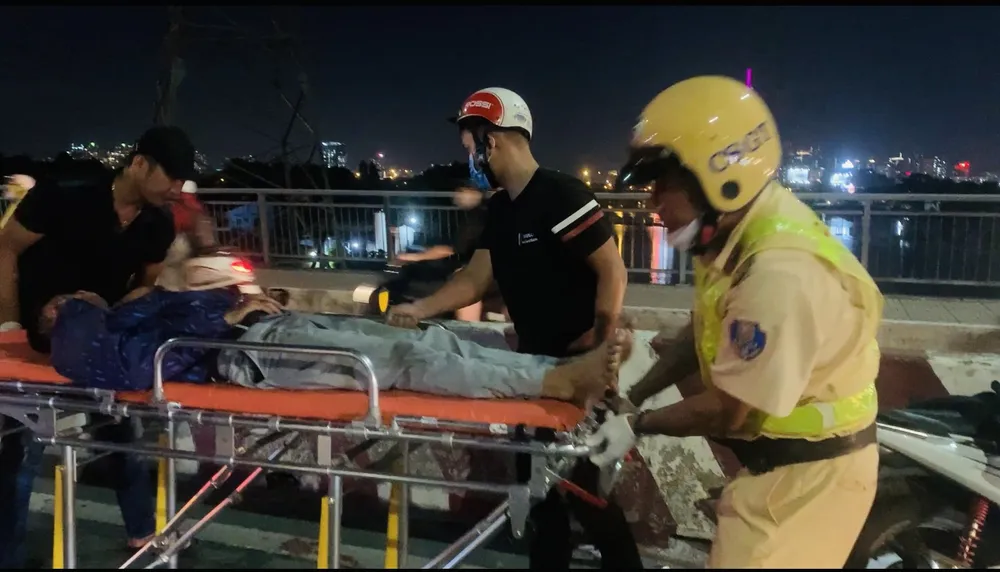 Hai CSGT Đội CSGT Hàng Xanh hỗ trợ, đưa người gặp nạn đi cấp cứu. Ảnh: CHÍ THẠCH