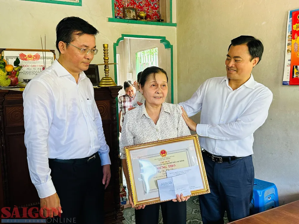 Phó Chủ tịch UBND TPHCM Bùi Xuân Cường trao bằng khen mừng thọ cụ Võ Thị Láng cho người thân, gia đình. Ảnh: CHÍ THẠCH