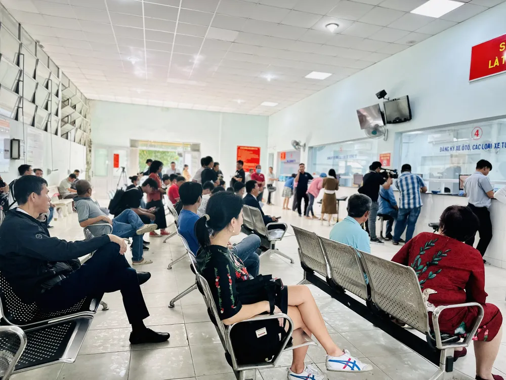 Người dân ngồi chờ làm thủ tục. Ảnh: CHÍ THẠCH