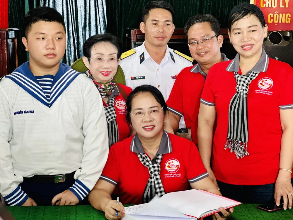 Chủ tịch Ủy ban MTTQ Việt Nam TPHCM Trần Kim Yến viết sổ tặng cán bộ chiến sĩ Nhà giàn DK1/10. Ảnh: CHÍ THẠCH