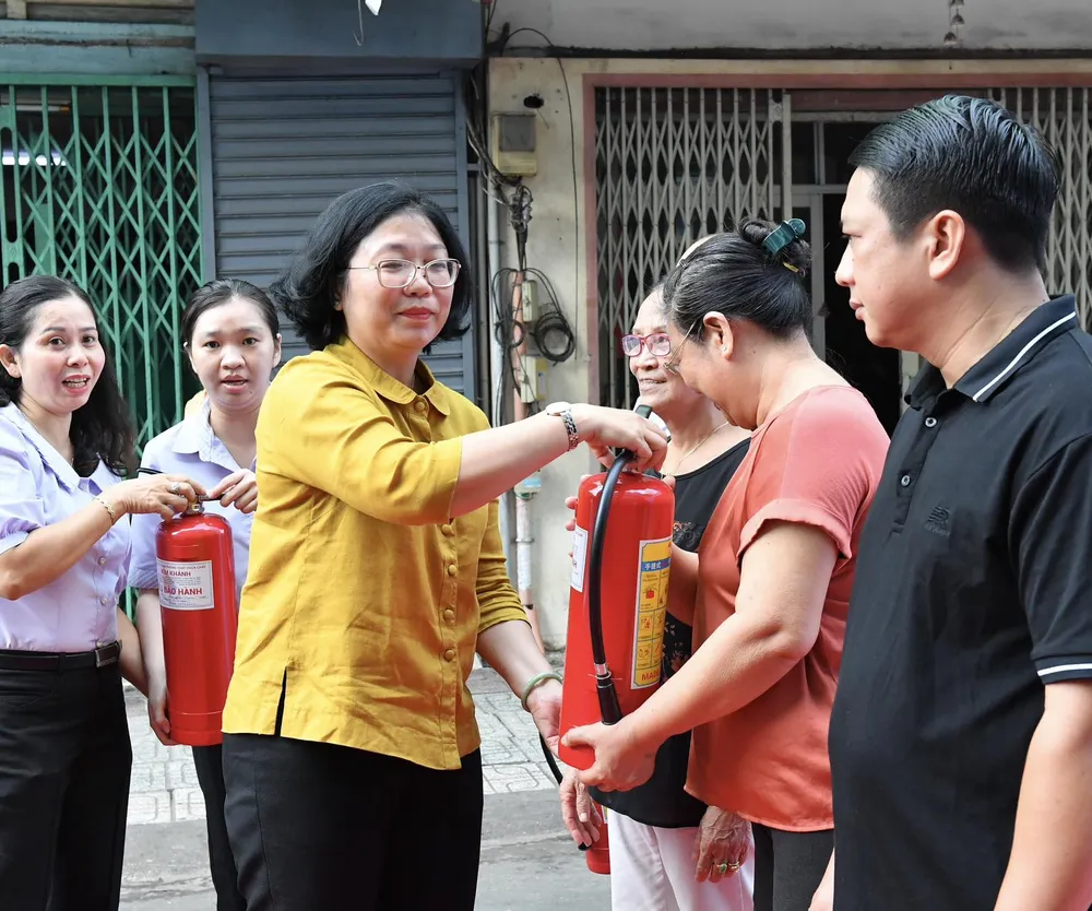 Bí thư quận ủy quận 5 Huỳnh Ngọc Nữ Phương Hồng trao tặng bình chữa cháy đến các hộ dân. Ảnh: VIỆT DŨNG