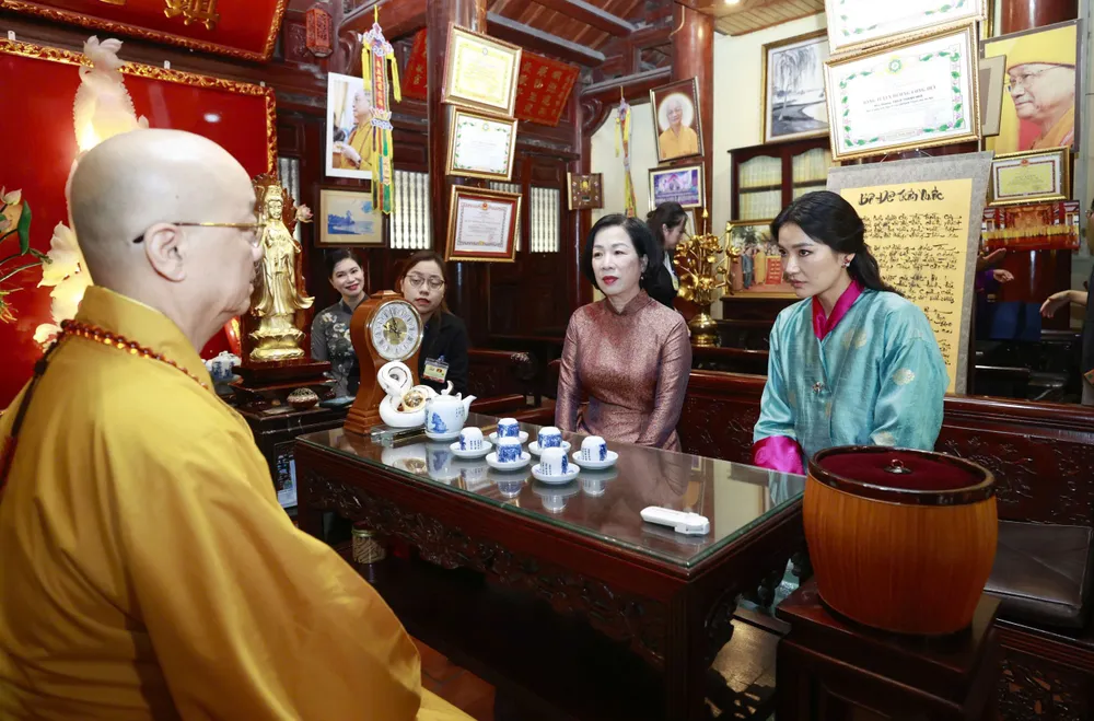 Phu nhân Nguyễn Thị Minh Nguyệt và Hoàng hậu Jetsun Pema Wangchuck thưởng trà, nghe Hòa thượng Thích Thanh Nhã, Trụ trì chùa Trấn Quốc giới thiệu về lịch sử chùa, ý nghĩa chiếc lá bồ đề được lấy từ cây bồ đề trồng ở sân chùa, ướp hương liệu, ép khô và khai quang trì chú, sáng 19-8. Ảnh: VIẾT CHUNG