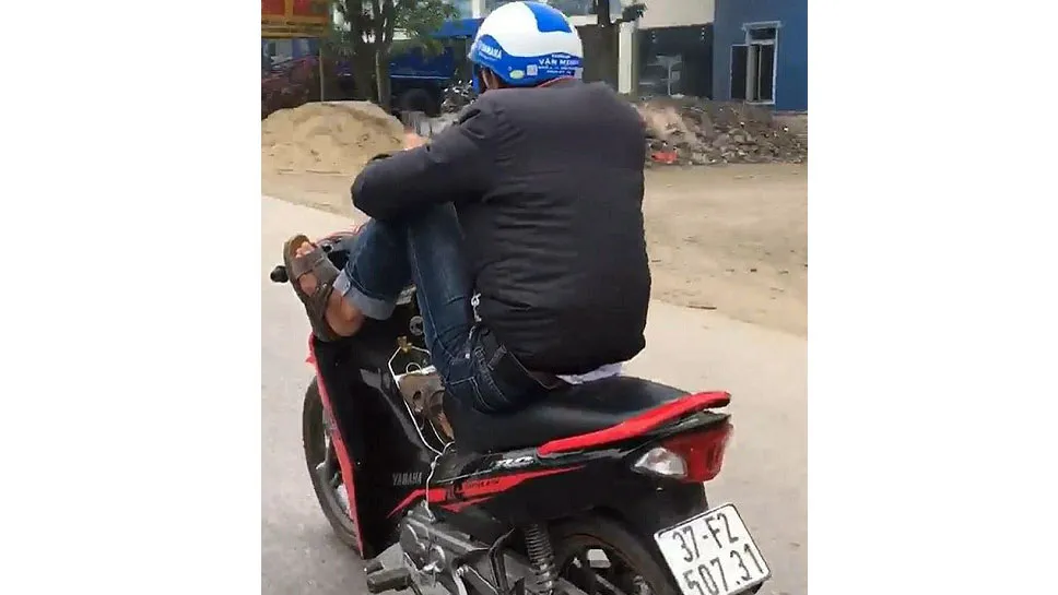 Nam thanh niên vừa dùng điện thoại vừa chạy xe bằng 2 chân. Ảnh cắt từ clip