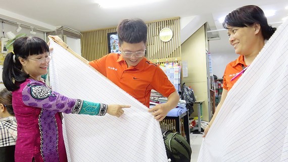 吳氏雲（左）指引新員工檢查產品質量。