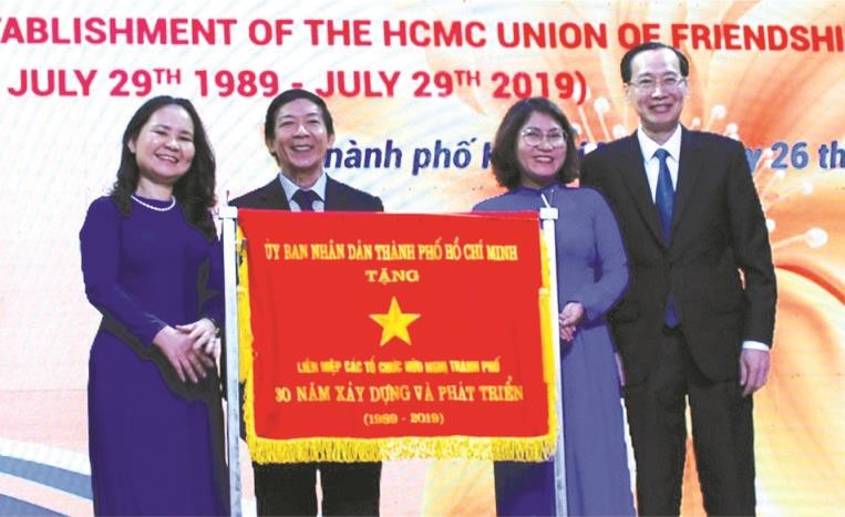 市人委會常務副主席黎清廉(右一)向市友聯會領導贈送市人委會傳統錦旗。