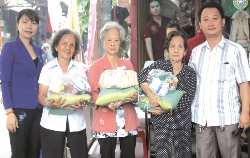 富山五行廟慈善組組長鄒國榮(右一)與第十五坊祖國陣線委員會主席阮玉錦(左一)向貧困長者贈送禮物。