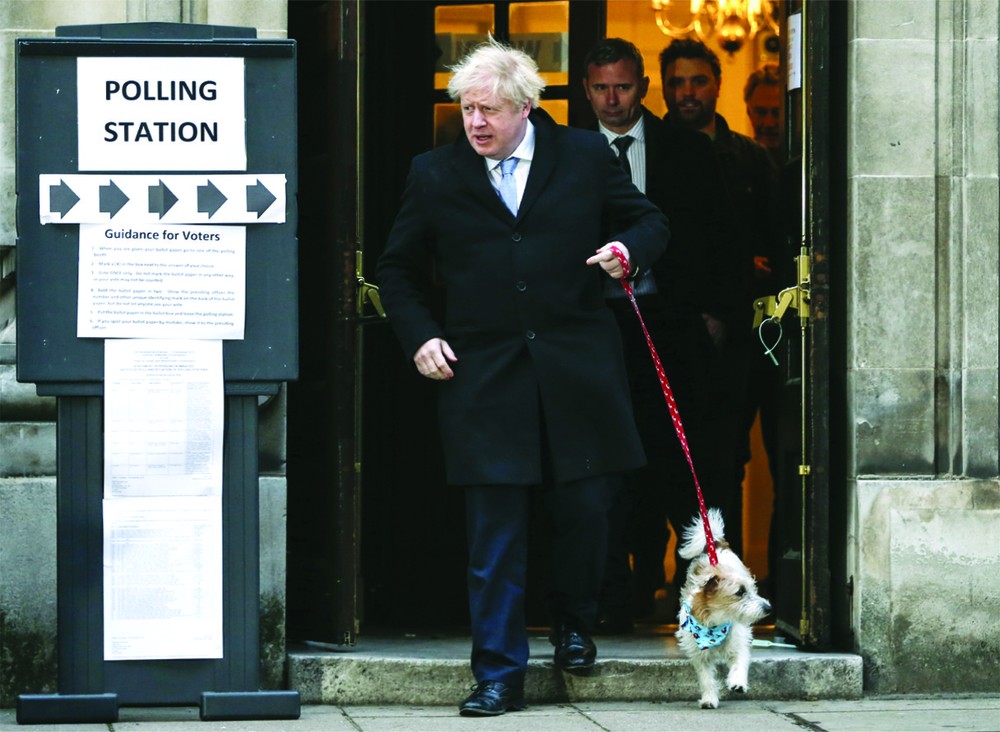 英國首相鮑里斯‧約翰遜在一個投票站投票後牽著他的小狗離開。