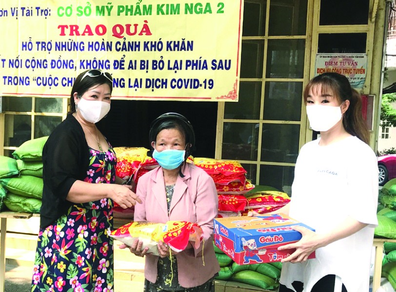 梁柳嬋(左一)與媳婦(右一)向窮人贈送禮物。