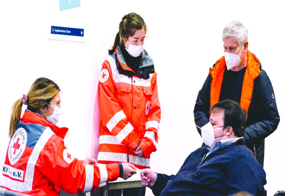 德國埃森展覽館的新冠疫苗接種中心工作人員為訪客進行登記。