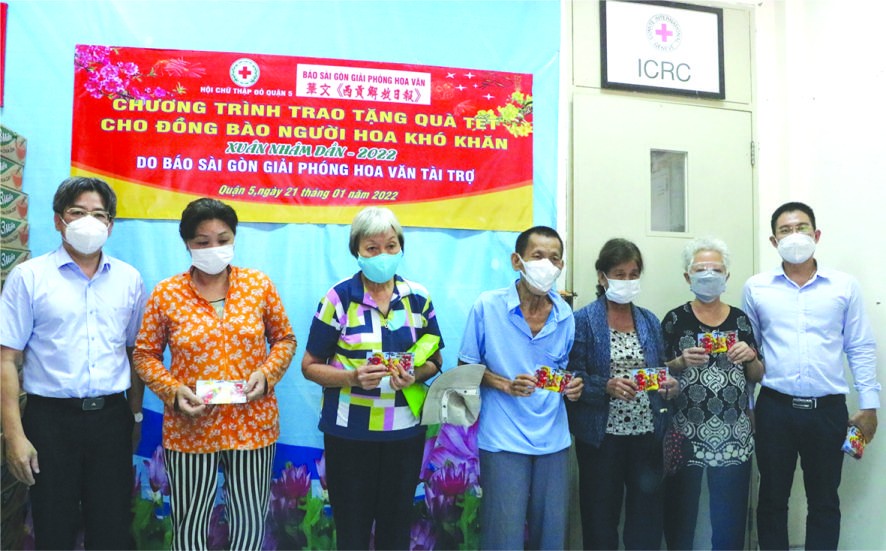 第五郡人委會副主席阮武春奇(左)、本報 編委文忠孝(右)向華人同胞贈送禮物代金。