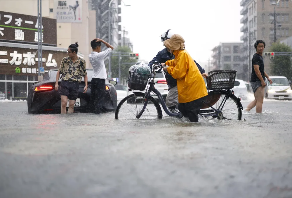 Người dân băng qua một con đường ngập lụt ở Nagoya (Ảnh: THX)