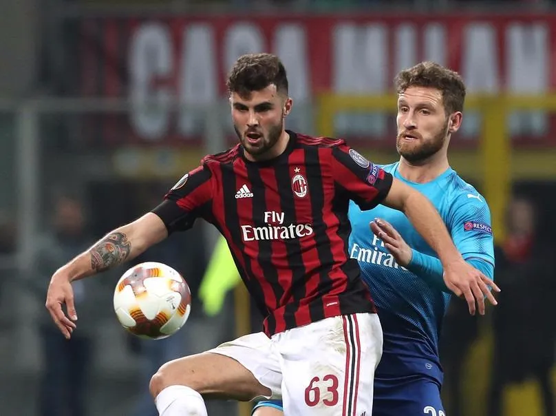 Patrick Cutrone (trái, AC Milan) tranh bóng với Shkodran Mustafi (Arsenal)