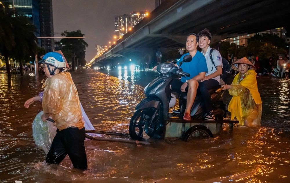 9月30日晚，河内市民使用载摩托车通过水淹路段服务。