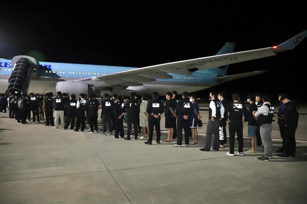 10月18日凌晨，在柬埔寨金边德崇国际机场，警察押送被遣返的韩国网络诈骗嫌疑人登机。