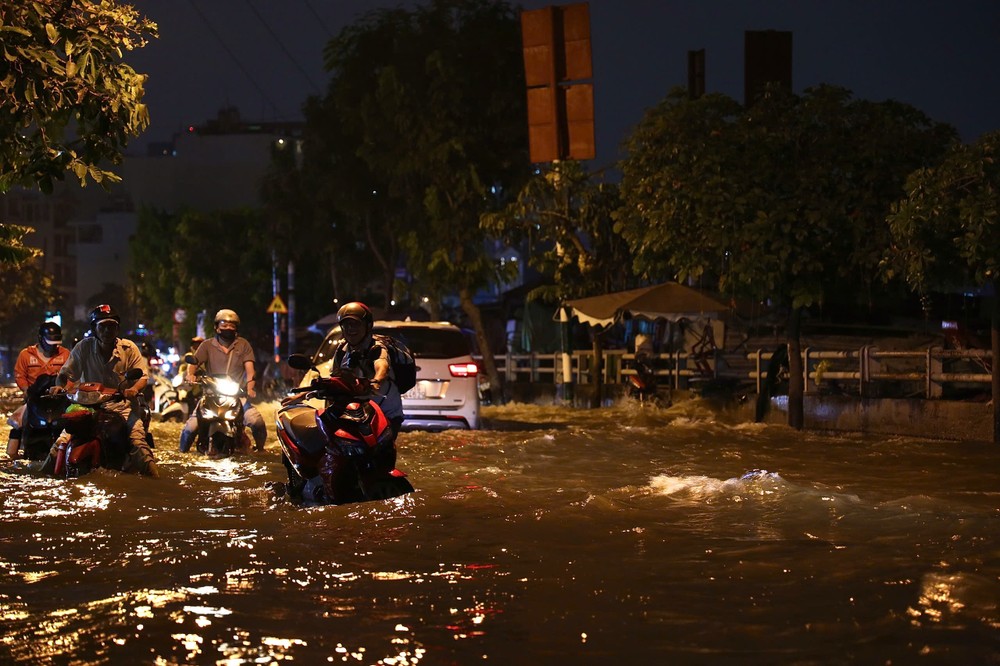 胡志明市新顺坊陈春撰街潮汛仍高涨，河水涌入民房，导致交通堵塞 。
