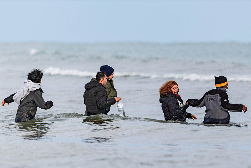 2024年4月26日，在法国北部敦刻尔克附近的格拉沃利讷海滩，移民走进大海准备乘橡皮舟渡海前往英国。