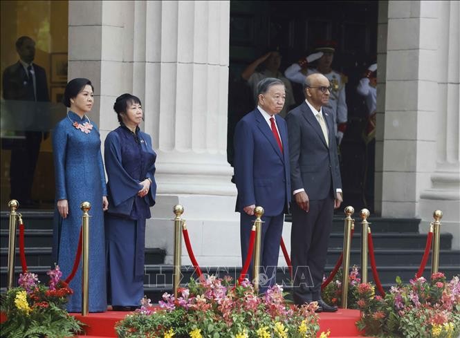 党中央总书记、国家主席苏林和新加坡总统尚达曼在荣誉台上，聆听军乐队奏两国国歌。图源：统一/越通社。