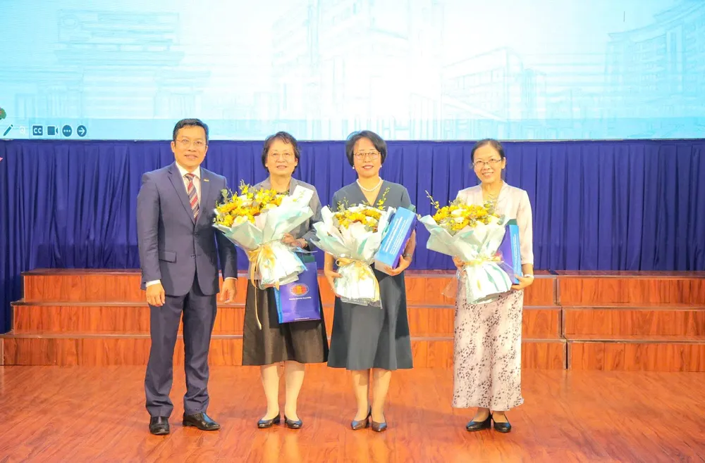 Đại diện Trường ĐH Khoa học xã hội và Nhân văn trao hoa và quà lưu niệm đến các chuyên gia tham gia tập huấn.