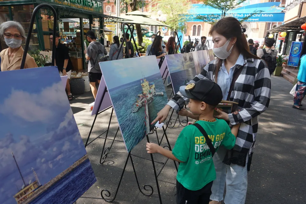 Phụ huynh dẫn con xem những hình ảnh về Trường Sa tại Đường sách TPHCM tại chương trình ra mắt sách