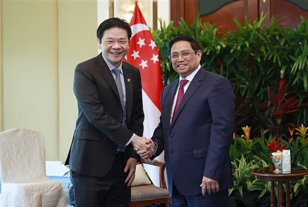 Prime Minister Pham Minh Chinh (R) shakes hands with Singaporean Deputy Prime Minister Lawrence Wong. (Photo: VNA)