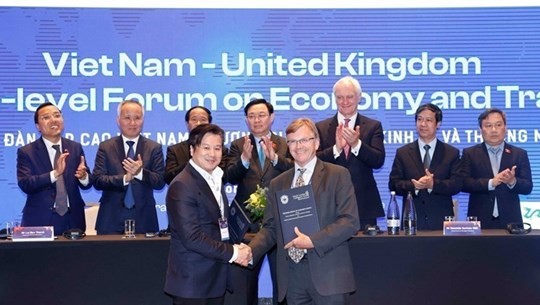Chairman of the Vietnamese National Assembly Vuong Dinh Hue (behind, center) witnesses the exchange of cooperation agreements between businesses and localities of Vietnam and the UK at a high-level forum on economy and trade between the two countries in London in June 2022. (Photo: VNA)