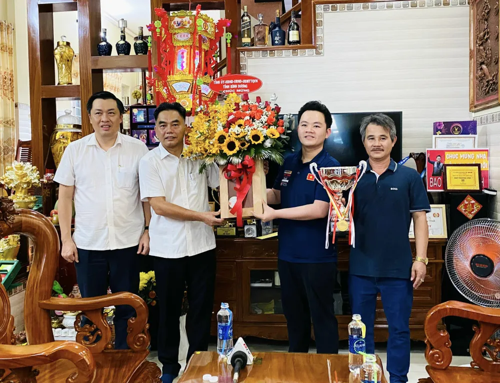 Ông Nguyễn Lộc Hà - Phó chủ tịch UBND tỉnh Bình Dương thay mặt lãnh đạo tỉnh Bình Dương tặng hoa và quà chúc mừng nhà vô địch thế giới Bao Phương Vinh tại nhà riêng. Ảnh: THÁI HẢI