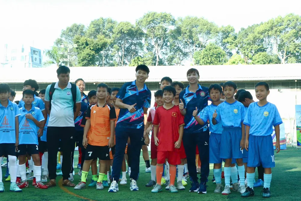 Các nữ tuyển thủ quốc gia Kim Thanh, Thùy Trang chụp hình lưu niệm cùng các cầu thủ nhí. Ảnh: HTV