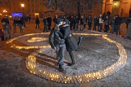 Trước sự cổ vũ của mọi người, một cặp hôn nhau trong một trái tim bằng các cây nến thắp sáng tại thành phố Lviv (Ukraine) (AP)