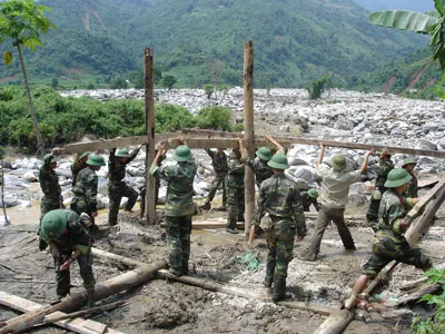Bộ đội giúp dân dựng lại nhà sau khi lũ quét ở bản Tùng Chỉn (Bát Xát, Lào Cai) tháng 8-2008. Trận lũ quét này là hậu quả của bất cập trong công tác dự báo thiên tai. Ảnh: VĂN NGHĨA