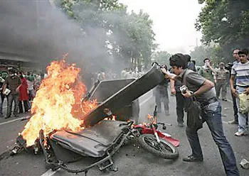 Thanh niên đốt chướng ngại vật trên đường phố Tehran. Ảnh: REUTERS