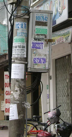 Cột điện hay cột số? Nhiều quảng cáo dán và sơn trên cột điện, bất chấp sự nguy hiểm (ảnh chụp trên đường Trương Định). Ảnh: Đ.H.