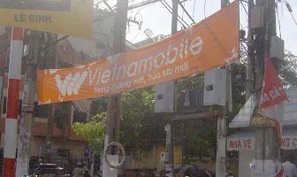 Băng rôn quảng cáo cũ đang quấn ngoằn ngoèo trên cột điện, băng rôn quảng cáo mới lại treo lên (ảnh chụp sáng nay trên đường Hoàng Văn Thụ - Tân Bình). Ảnh: H.V.